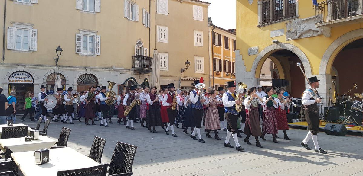 Eine Musikkapelle in ladinischen Trachten spielt auf dem Platz vor dem Municipio in Muggia auf